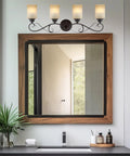 Traditional 31 Inch Four Light Vanity Light With Scrollwork Arms And Frosted Amber Glass Shades In Oil Rubbed Bronze Finish over mirror
