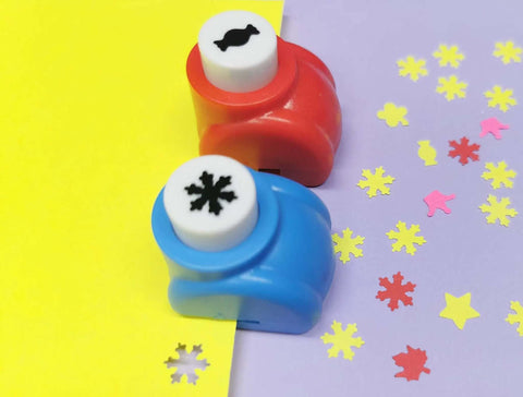 Two hole punches from 10 Piece Hole Punch Craft Set with colorful scrapbooking shapes, including snowflakes and candy designs on paper.
