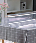 Clear 24 By 60 Inch Table Protector 1.5mm Thick PVC Desk Mat shown partially rolled on a table with a vase and shelf in the background.