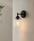 AOIOUR 10.4" 1‑Light Farmhouse Vanity Wall Sconce, Ribbed Glass Matte Black mounted on a wall with soft illumination.