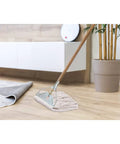 Industrial Grade 59 Inch Quick Change Mop Stick With Wooden Handle And Steelhead on wooden floor near rug