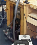 Heavy Duty Cyclone Dust Collector With High Efficiency HEPA Filtration And Remote Switch Box in a workshop with a vacuum hose.