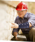 Slip On These Hella Tough Cut Resistant Arm Sleeves For Reliable Lightweight Wrist Guard Protection Built For Mechanic Jobs Welding And Outdoor Projects, worn by a worker inspecting a wall.