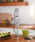 Hassle Free Variable Speed Corded Hand Blender With Razor Sharp Stainless Steel Blades For Smoothies Soups And Hummus on a kitchen counter.