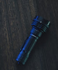 Defender P18 Tactical Flashlight With Dual Tail Switch 5000 Lumen LED on dark wood surface, showing rugged design and reverse clip