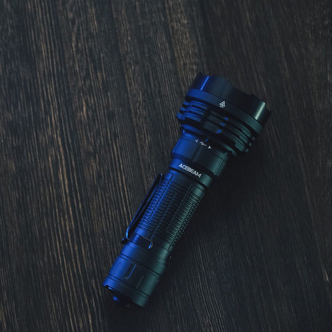 Defender P18 Tactical Flashlight With Dual Tail Switch 5000 Lumen LED on dark wood surface, showing rugged design and reverse clip