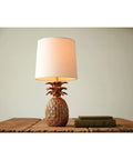 Coastal Pineapple Table Lamp with linen shade on wooden table; distressed finish creates beach vibe, 18" tall with 62in cord.