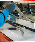 Manual Metal Bender Tool With Straight Jaw Hand Seamer for duct crimping displayed on a metalwork table next to machinery.