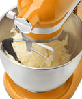 Orange mixer with Flex Edge Beater Replacement for KitchenAid Tilt-Head Stand Mixers, 4.5-5 Quart, mixing dough in a metal bowl.