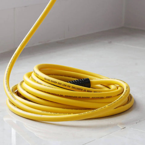 Coiled yellow air compressor hose, 1/4 inch by 25 feet hybrid, with fittings. Suitable for home shop use, flexible in various weather conditions.