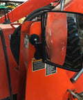 Side view of a red tractor with a side mirror reflecting a wheel