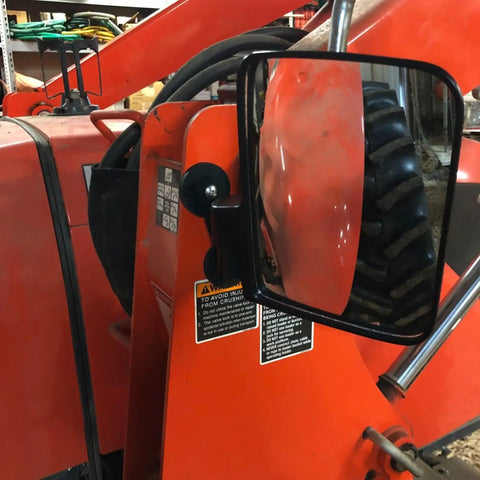 Side view of a red tractor with a side mirror reflecting a wheel