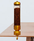 Straight Up Premium Coffee Bean Storage Canister Keeping Beans Extra Crisp In A Top Shelf Gold Tube Jar For Whole Grains And Snacks Kitchen Pantry Display Jar on a table with coffee beans visible inside.