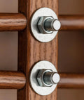 Close-up of two metal bolts with washers and nuts mounted to a wooden post