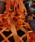 Orange flat nylon lifting slings tangled on a workbench for hoisting and rigging.