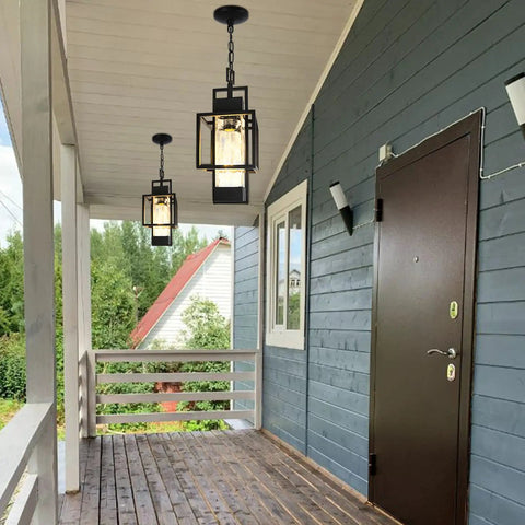 Top Tier 15 Inch Outdoor Indoor Pendant Light Featuring Heavy Duty Black Metal And Thick Water Seeded Glass hanging on a porch.
