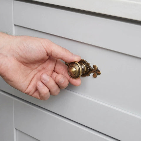 Person opening a drawer using Top Shelf Vintage Zinc Alloy Cabinet Handles With Backplate And Secure Screws 4 Pack.