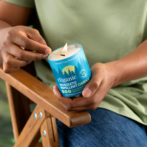 Person holding lit Citronella Mosquito Repellent Candle Pack Of 2 For Outdoor Adventures Camping With Essential Oils Soybean And Beeswax Burns 18 Hours DEET Free Naturally Scented With Rosemary And Lemongrass For Outdoor Relaxation.