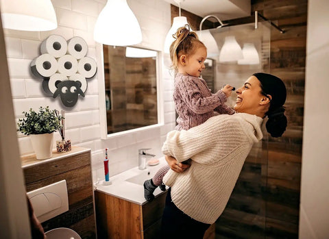 Bathroom with woman holding child, displaying a Sheep Toilet Paper Holder Stand And Wall Mount Shelf For Bathroom Storage Space Saver Farmhouse Decor Holds Up To 7 Rolls 8 Optional Freestanding Or Wall Mounted Organizer Rack.