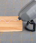 Genesis Cordless Hot Glue Gun With Quick 25 Second Preheat USB Charge shown applying glue on wooden block, ergonomic design