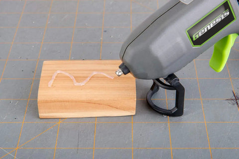 Genesis Cordless Hot Glue Gun With Quick 25 Second Preheat USB Charge shown applying glue on wooden block, ergonomic design
