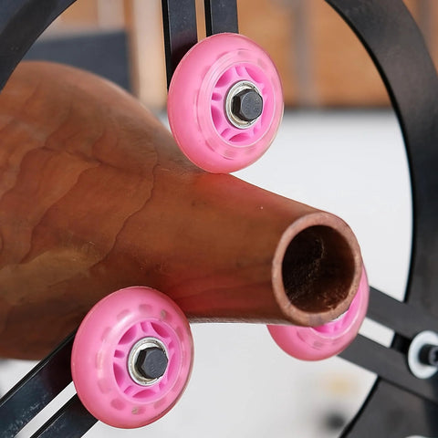 Close-up of BMWOOD Woodturning Steady Rest MC-FS7 with pink nylon wheels mounted on a lathe, supporting a spindle.