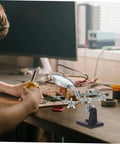 Person using Adjustable Third Hand Soldering Station With Magnifying Glass And Dual Alligator Clips for PCB repair on a desk