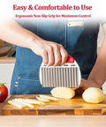 Crinkle cutter with stainless steel blade and red ergonomic handle slicing potatoes on a wooden cutting board.