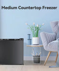 Hella Compact Yet Hella Spacious 1.1 Cu Ft Small Upright Freezer in matte black next to a chair and plant on a light floor.