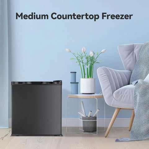 Hella Compact Yet Hella Spacious 1.1 Cu Ft Small Upright Freezer in matte black next to a chair and plant on a light floor.