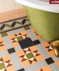 Square 4 Inch Shower Drain With Flange And Removable Quadrato Pattern Grate In Matte Black beside a green bathtub on colorful tiles.