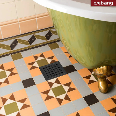 Square 4 Inch Shower Drain With Flange And Removable Quadrato Pattern Grate In Matte Black beside a green bathtub on colorful tiles.