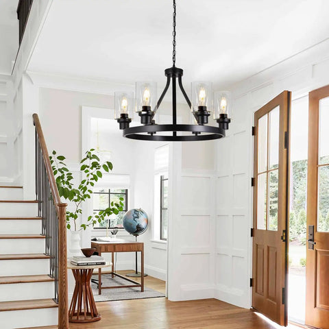 Six Light Farmhouse Wagon Wheel Chandelier Pendant Light Fixture In Matte Black in a bright foyer with wooden floors