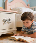 Boy reading near dresser with Pink And Silver Bow Dresser Knobs For Kids Rooms, Zinc Alloy 3D Decorative Drawer Pulls