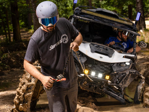 Front view of a UTV with a 4500 lb SuperATV Black Ops winch kit installed in mud.