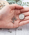 Hand holding Antique Silver Tibetan Style Pumpkin Spacer Beads 4mm, 100 Piece Set with a coin for size reference.