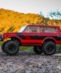 Redcat Racing Ascent 18 Scout II Brushless 4x4 RC Crawler on rocky terrain, aluminum chassis, red gold dust finish