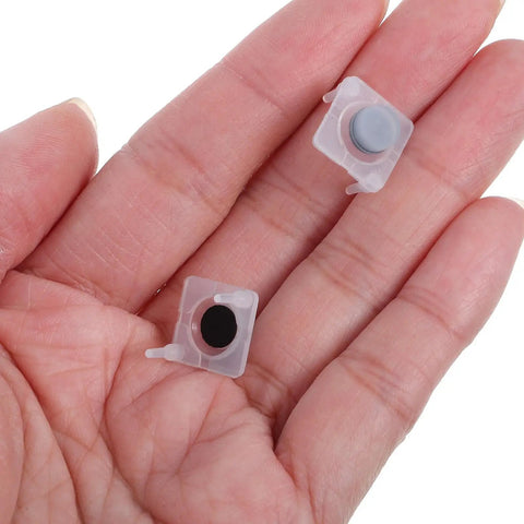 Two silicone push button switches in a hand, part of the 40 Piece Silicone Push Button Switch Replacement Keypad Membrane.