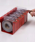 Modular Sandpaper Dispenser For Dedicated Woodworkers Includes Six Aluminum Oxide Rolls, red holder with a hand pulling sandpaper.