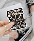 Plane Techs And Pilots Sticker Pack: We Fix What Your Pilot Breaks Funny Aviation Maintenance Decals held in hand over laptop.