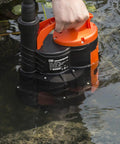 Person placing Heavy Duty Submersible Water Pump 1HP 3500 GPH With Built In Float Switch in water for drainage