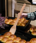 Person using Monster 18 Inch Wooden Stir Paddle For Crawfish Boil Big Pots Heavy Duty Cajun Spatula with rolls on baking tray