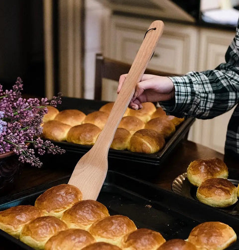 Person using Monster 18 Inch Wooden Stir Paddle For Crawfish Boil Big Pots Heavy Duty Cajun Spatula with rolls on baking tray