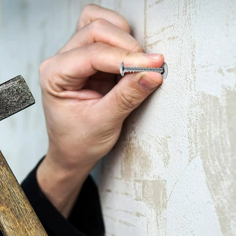 Hand holding Heavy Duty Self Drilling Drywall Anchors And Screws Kit against wall for installation