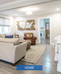 Modern living room with beige sofas, wooden armchair, and wall art. Lit 6500 Lumen A21 LED Bulb Replaces 450W Incandescents, 5000K Daylight, 35W, E26 Non Dimmable, 25,000 Hour Lifetime, Flicker Free, Energy Efficient Home Office And Workshop Lighting.
