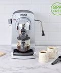 Compact Electric Bistro Style Espresso And Cappuccino Maker With Durable Glass Carafe on a marble countertop with two cups.
