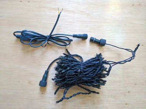 33Ft 100 LED Outdoor Waterproof String Lights Warm White For 12V Low Voltage Landscape Lighting coiled on a wooden surface