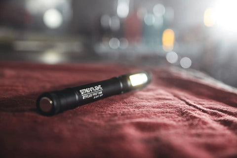 Stylus Pro COB Rechargeable Penlight Work Light with Magnetic Base resting on red fabric, black finish visible