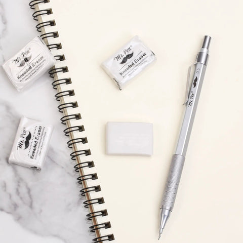 Kneaded Art Erasers Four Pack White Soft Moldable Erasers For Charcoal Graphite And Pastel Drawing next to sketchbook and pencil