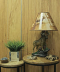 Wildlife Moose Table Lamp With A 12 Inch Forest Print Lampshade For Living Rooms Cabins And Bedrooms Delivers Cozy Warm Glow And Striking Rustic Decor Standing 20 Inches Tall For A Commanding Home Accent on wooden table with plant and decor